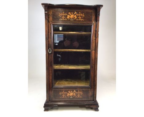 A Gillows style rosewood music cabinet with extensive inlay, glazed door to material lined shelves, brass handle and hidden c