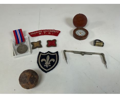 A collection of military items including the war medal 1939-1945, a cannon ball, a wooden cased compass, shoulder flashes fro