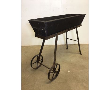A wooden planter trough on cast metal wheeled baseW:99cm x D:40cm x H:80cm