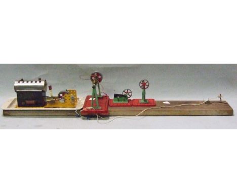 A Meccano horizontal stationary steam engine together with a Mamod line shaft and two drop hammers, all mounted on a plank.
