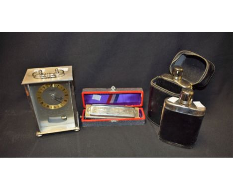 A pair of hip flasks, cased; a harmonica; a mantel clock (3)