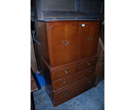 A reproduction Oak finished Cupboard on Chest of small proportion with moulded edge top over pair of single panel opposing do