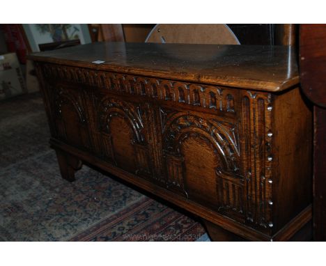 A good quality reproduction Oak Sword style six-plank Chest with moulded edge top and carved front in the style of three pane