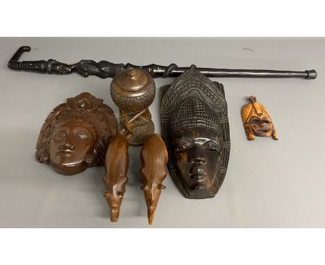 Collection of carved wooden masks, rhino figures, a walking stick and a wooden figure of a man holding a bowl