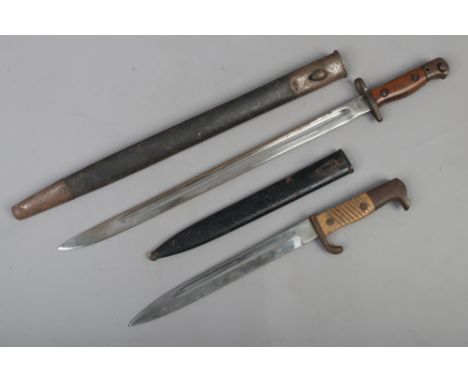 A World War I British bayonet in black leather scabbard, broad arrow mark to blade, along with another shorter bayonet (unmar