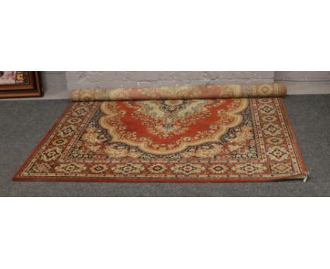 A maroon ground wool carpet square decorated with stylized flowers and a centre medallion.