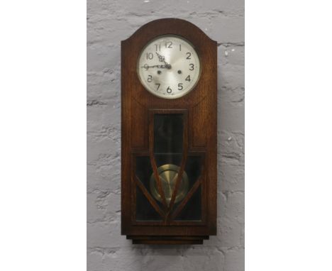 An oak cased Enfield wall clock with silvered dial, chiming on a coiled gong.