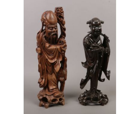 A Chinese carved hardwood model of a sage holding a staff along with a similar Chinese statue.