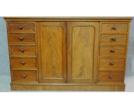 A Regency mahogany press cupboard with fitted central panel doors enclosing linen slides, flanked by drawers fitted with reed