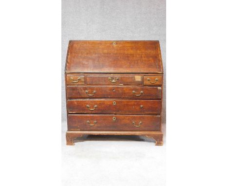 A Georgian oak bureau with fall front revealing fitted interior above three short and three long graduating drawers on bracke