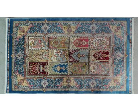 A Persian silk rug with repeating tile design with stylised floral motifs, within border with flowers, birds and animals on a