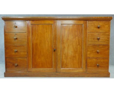 A mid 19th century mahogany press cupboard fitted central section with panel doors enclosing linen slides flanked by four dra