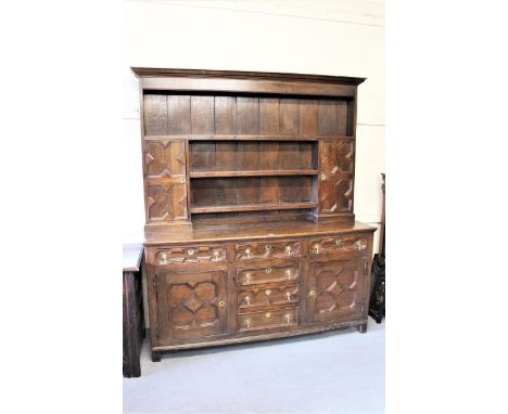 18th Century oak dresser with geometric moulding decorations, the boarded shelf and cupboard back above two doors and six dra