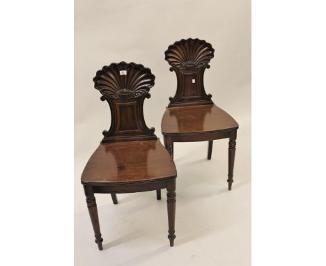 Pair of Regency mahogany hall chairs, the finely carved shell backs above panel seats and turned tapering front supports 