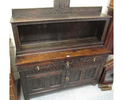 Oak dresser with an open shelf back above three carved drawers and two carved panelled doors, raised on low bun feet, 19th Ce