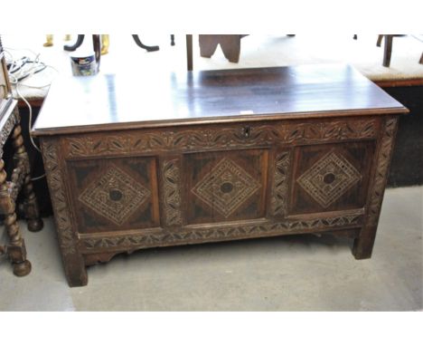 17th Century oak coffer, the hinged moulded plank lid above a carved three panel front with additional stained decoration, ra