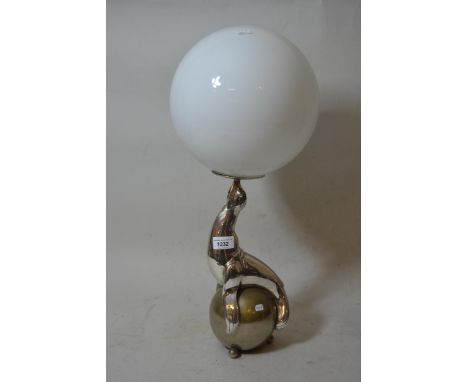 Silvered metal lamp base in the form of a performing seal with an opaque glass globe shade, 22.5ins high overall 