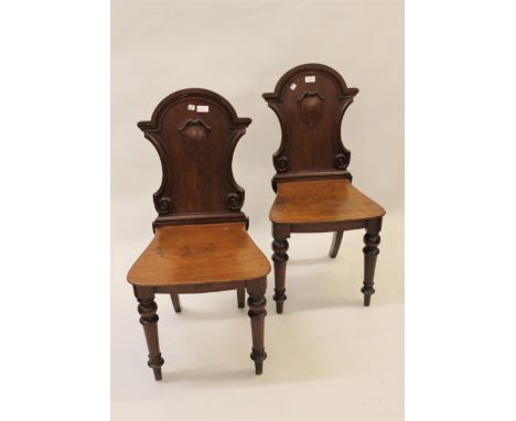 Pair of Victorian mahogany hall chairs, the shield backs above panel seats and turned tapering front supports 