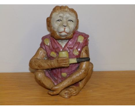 A novelty ceramic figure of a seated monkey holding a pipe, 7.25" high - a/f.