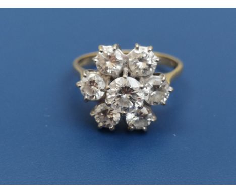 A seven stone diamond cluster ring, the largest brilliant to centre measuring 5.4mm diameter, on 18ct gold shank.  Finger siz