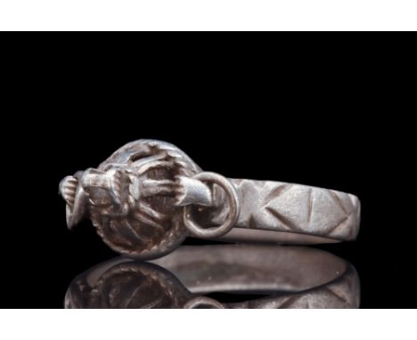 Ca. 600 AD.A silver finger ring with a flat section hoop adorned with delicate etchings that grace its exterior surface. The 