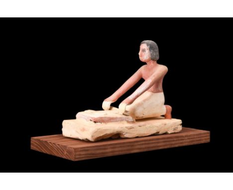 Middle Kingdom, ca. 2030-1650 BC.A model of a woman grinding grain is a captivating artifact crafted from wood, coated with g