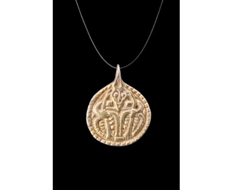 Ca. 900-1000 AD.A circular gilt silver pendant featuring one face decorated in a low relief depiction of Odin, the one-eyed g
