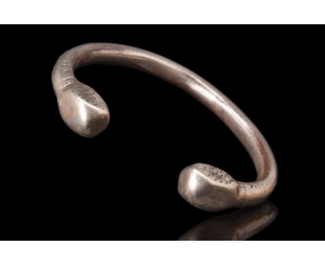 Ca. 1100-1200 AD.A silver bracelet with a round-section shank, skillfully modeled in the round, gracefully envelops the wrist