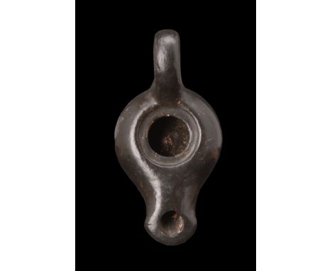 Ca. 400-300 BC.A pottery oil lamp adorned with a black glaze. It features a hollow rounded body with a central filling hole, 