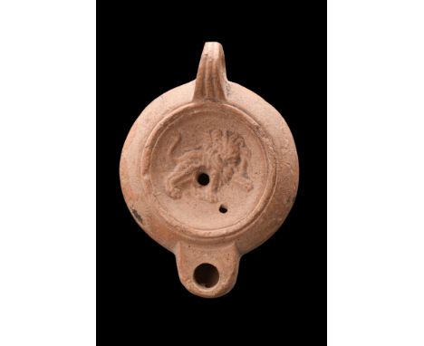 Ca. 200-300 AD.A terracotta oil lamp of the Loeschcke IV type characterized by its round body, sunken tondo featuring a finel