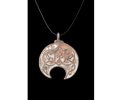 Ca. 1200-1400 AD.An amulet crafted from silver exudes an air of mystique with its crescent-shaped body. The gracefully curved