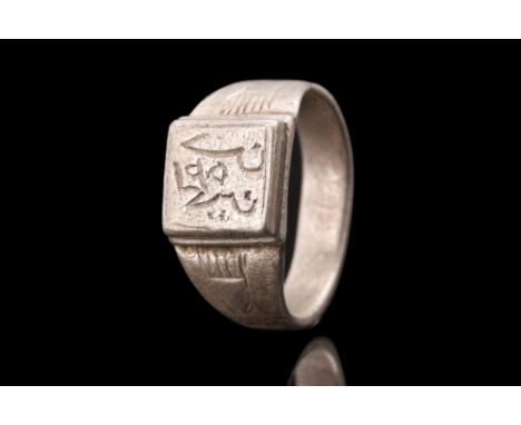 Ca. 1100-1200 AD.A silver ring featuring a round hoop with a flat-section profile that seamlessly expands to form an elaborat