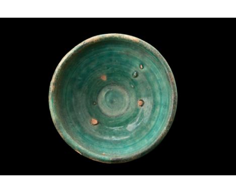 Ca. 1100-1200 AD.A green glaze pottery bowl, crafted with skill and precision, showcases the artistic mastery of the Kashan c