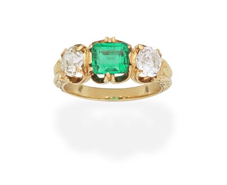 EMERALD AND DIAMOND THREE-STONE RINGThe octagonal cut emerald, between cushion-shaped diamonds, the hoop with engraved scroll