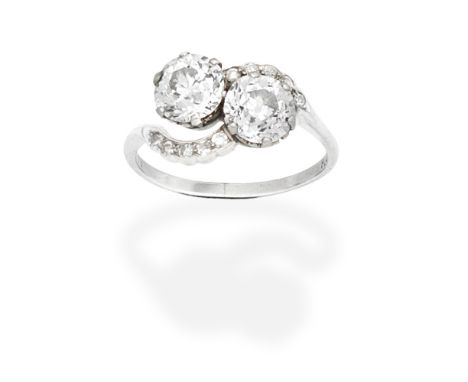 DIAMOND CROSSOVER RINGObliquely set with two old brilliant-cut diamonds, weighing 1.51 and 1.35 carats, between single-cut di