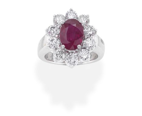 RUBY AND DIAMOND CLUSTER RINGThe oval-cut ruby, within a brilliant-cut diamond surround, mounted in 18 carat gold, diamonds a