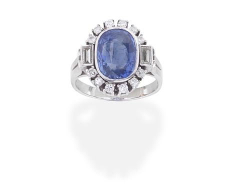 SAPPHIRE AND DIAMOND CLUSTER RINGThe oval-cut sapphire within a brilliant-cut and baguette-cut diamond surround, between bifu