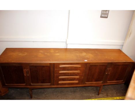 A large teak G-plan design sideboard fitted four central drawers, flanked by double cupboards, raised on rounded tapering sup
