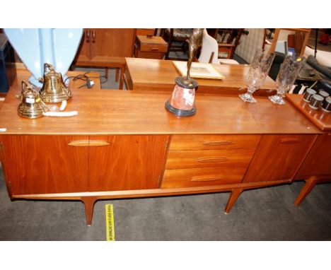 A teak G-plan design sideboard fitted three central drawers, flanked by double cupboard and drop flap drinks compartment rais