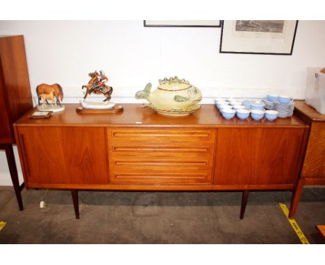 A teak G-plan design long sideboard fitted four central drawers flanked by sliding doors, raised on rounded tapering supports