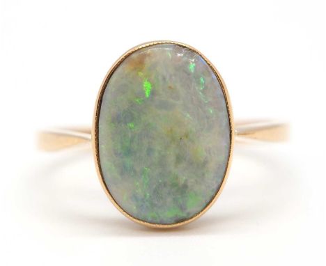 An opal ring, the oval opal cabochon in collet mount with open back and plain band stamped 18ct, size N, 2.1g
