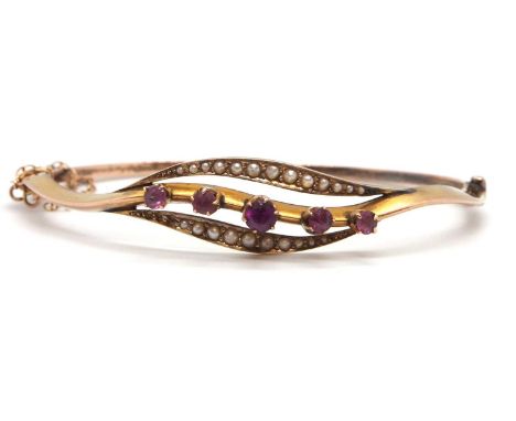 A 9ct pink stone and seed pearl bangle, the centre leaf shape frame set with five graduated round pink gemstones, claw mounte