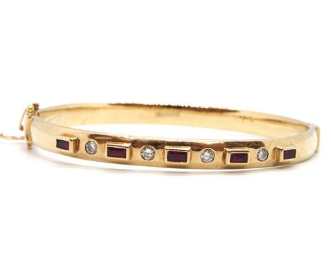 A 9ct ruby and diamond bangle, the hinged bangle with upper half set with alternating round brilliant cut diamonds and raised