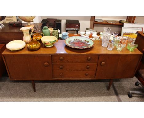 A G-plan design elm sideboard fitted three central drawers flanked by cupboards, raised on rounded tapering supports, 183cm w