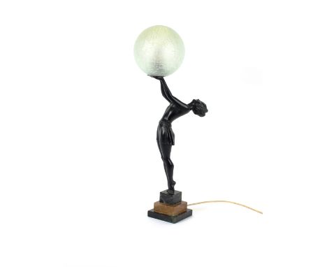 An Art Deco bronze table lamp, in the form of a semi-naked girl balancing a frosted glass globe, raised on stepped marble pli