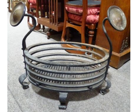 A 19th century iron fire grate of oval form, with integral copper panelled dogs, overall width 60cm