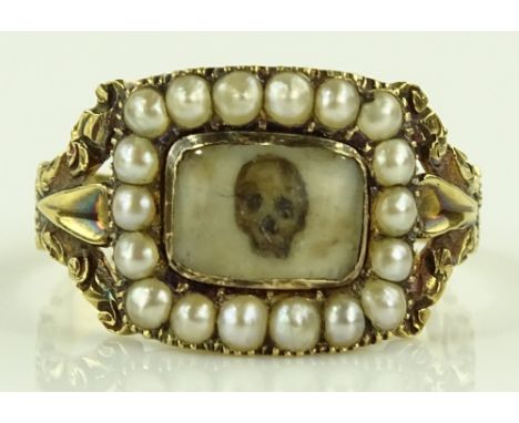 An Antique memento Mori skull panel ring, floral chased shoulders with seed pearl border, and painted skull on ivory panel, 1