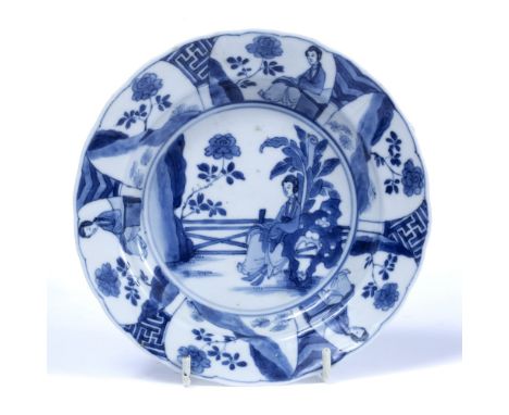 Blue and white saucer dish Chinese, Kangxi (1662-1722) decorated centrally with a lady sitting upon a natural rock set in a f