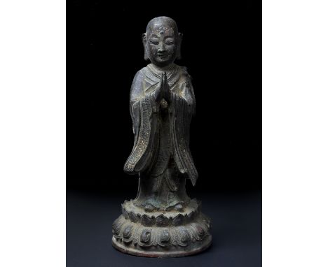 Bronze figure of a standing shaven headed priest Chinese, late Ming in prayer pose, dressed in long robes with traces of gilt