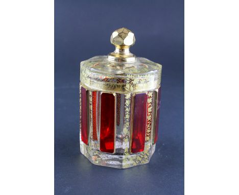 A Bohemian glass lidded jar, of lobed form, cut with ruby flashed panels and gilt scroll and diaper pattern, 11cm high